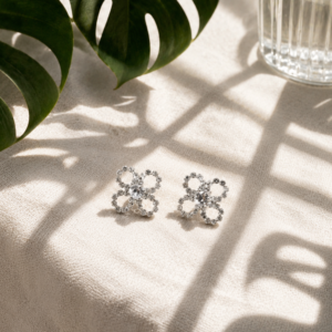 Crystal floral stud earrings with delicate silver-tone flower detailing on white textured background