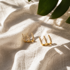 Gold triple row ear cuff earrings with crystal detailing on white background