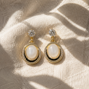 Gold oval pearl drop earrings with crystal detailing on white background