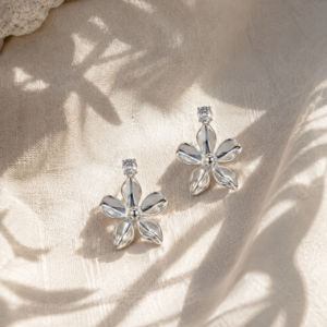 Elegant silver floral drop earrings with crystal accents on soft beige fabric background