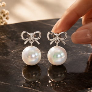 Pearl bow drop stud earrings with silver ribbon design and luminous pearl accents