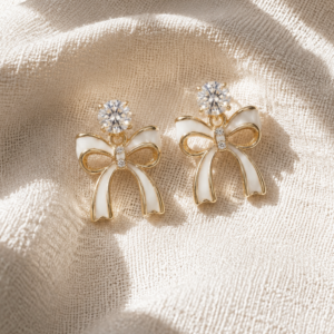 Gold bow stud earrings with ivory enamel details and crystal accents