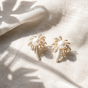 Gold pearl stud earrings with crystal starburst detailing on white background